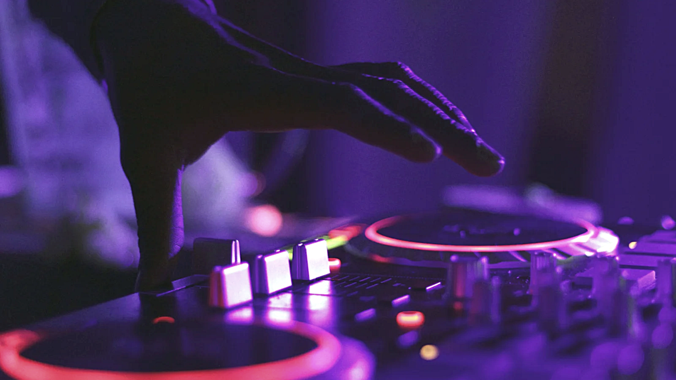 Renkli ışıklar altında DJ setup ve dans eden insanlar
